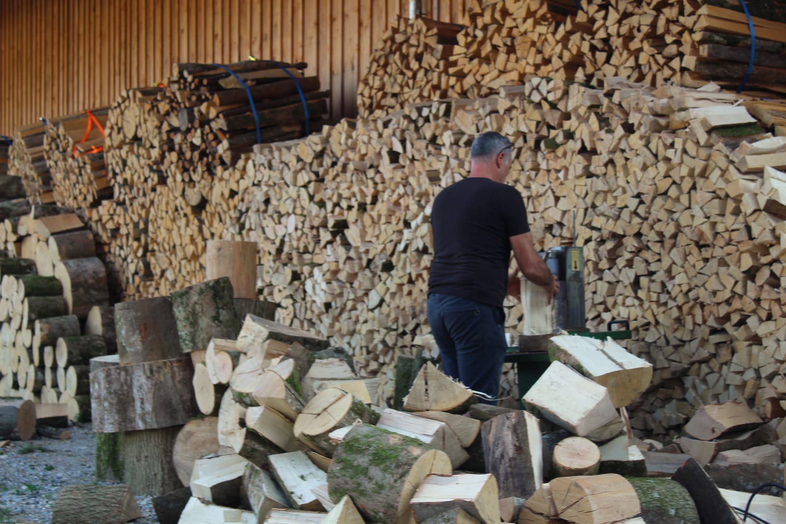 Holzspalten vor dem gestapelten Brennholz im Unterstand